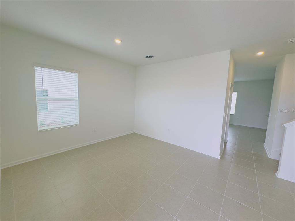 An empty room with white walls, tile flooring, and a window with blinds — 5872 MEDITATION DRIVE, CLERMONT, FL