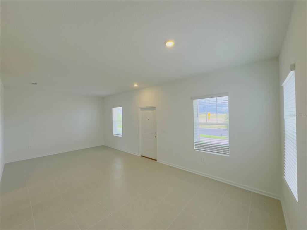 An empty room with white walls, tile flooring, recessed lighting, and several windows — 5872 MEDITATION DRIVE, CLERMONT, FL