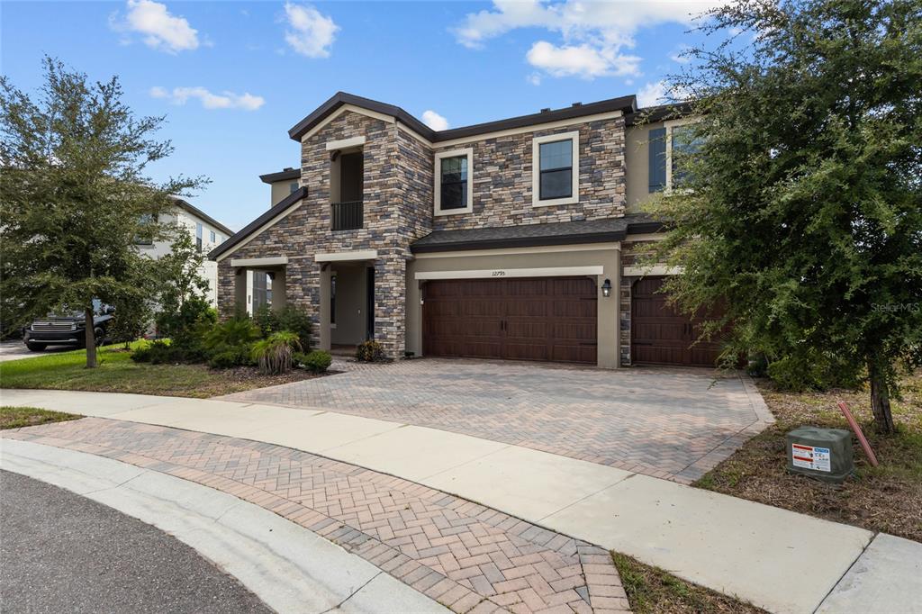 A two-story house with a stone facade, a three-car garage, and a paved driveway — 12795 FISHERVILLE WAY, RIVERVIEW, FL