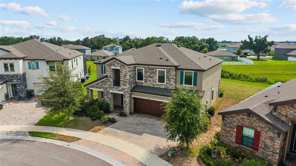 An aerial view shows a two-story suburban house with a stone facade and paved driveway — 12795 FISHERVILLE WAY, RIVERVIEW, FL