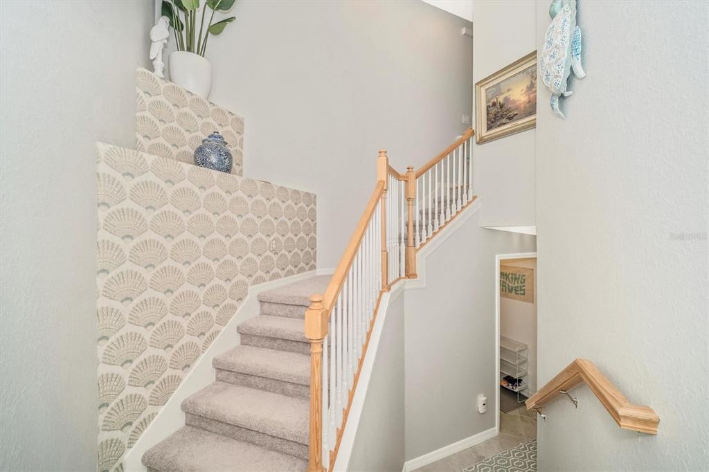 A carpeted staircase features a patterned accent wall, white railings, and a wooden handrail — 17740 BORACAY COURT UNIT 202, VENICE, FL