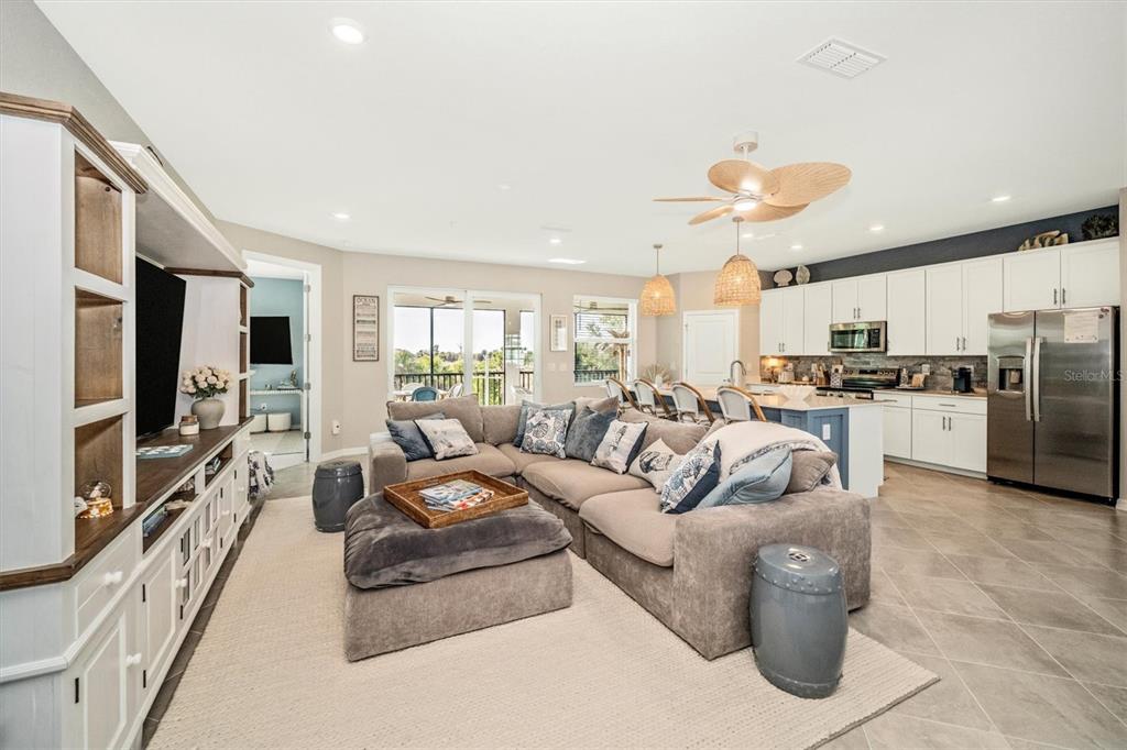 An open-concept living room and kitchen featuring a large sectional sofa and tile flooring — 17740 BORACAY COURT UNIT 202, VENICE, FL