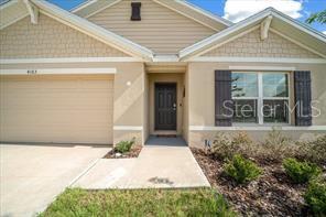 A beige single-story house features a two-car garage, a dark front door, and shuttered windows — 4163 SW 53RD LANE ROAD, OCALA, FL