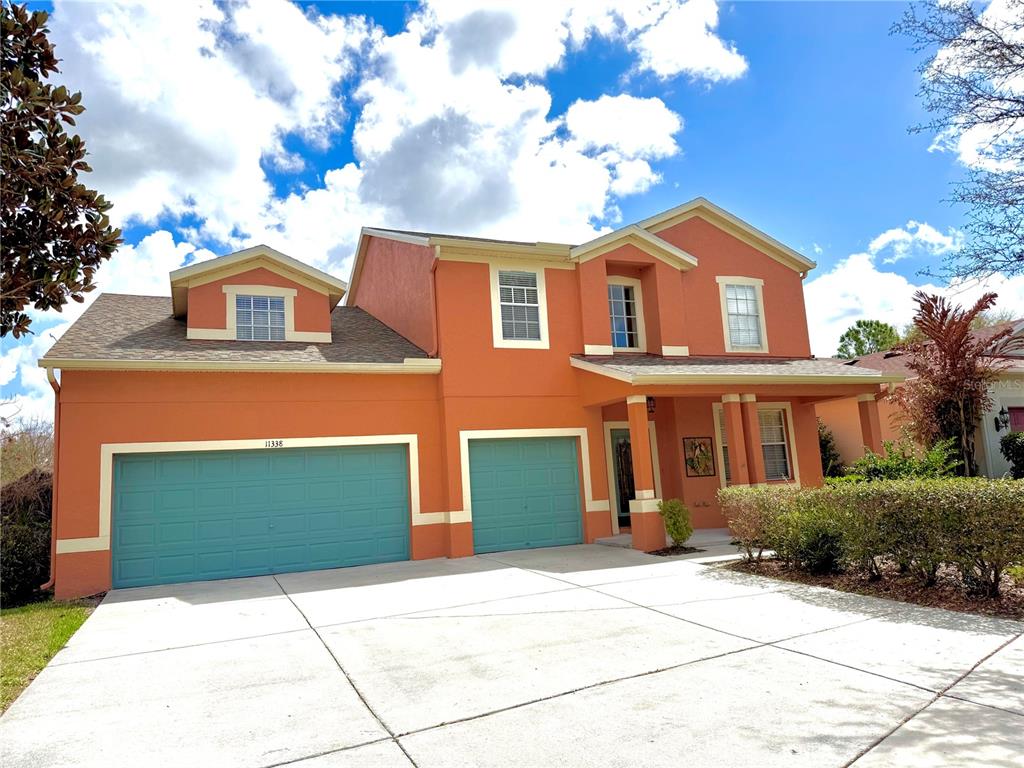 A two-story house with orange stucco siding, teal garage doors, and a concrete driveway — 11338 LAUREL BROOK COURT, RIVERVIEW, FL