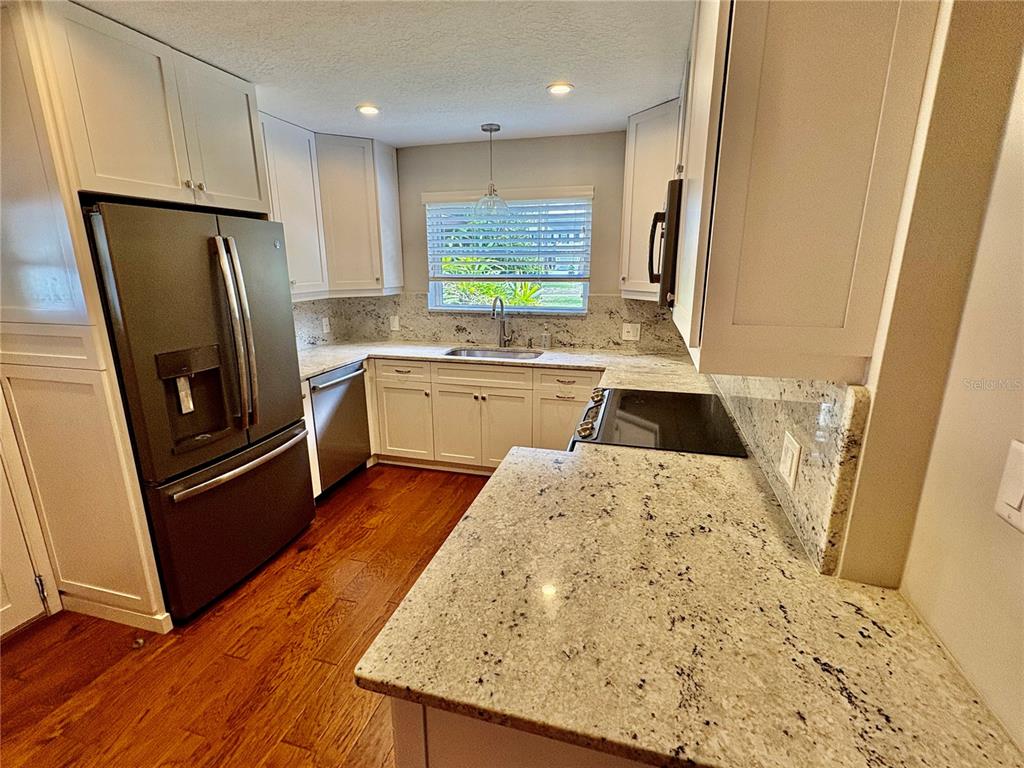 A kitchen features white cabinets, granite countertops, stainless steel appliances, and hardwood flooring — 438 LAKEVIEW AVENUE, WINTER PARK, FL