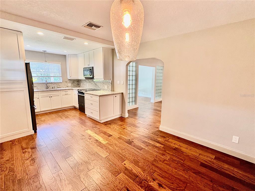 A kitchen with white cabinets, granite countertops, and hardwood floors opens to an adjacent room — 438 LAKEVIEW AVENUE, WINTER PARK, FL