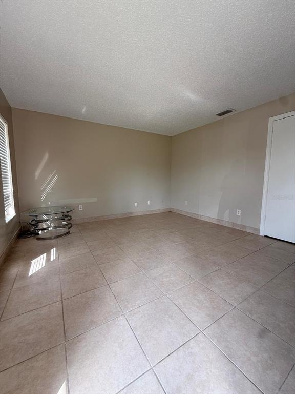An empty room with beige walls, tile flooring, and a glass-topped side table — 965 BRYAN COURT, LONGWOOD, FL