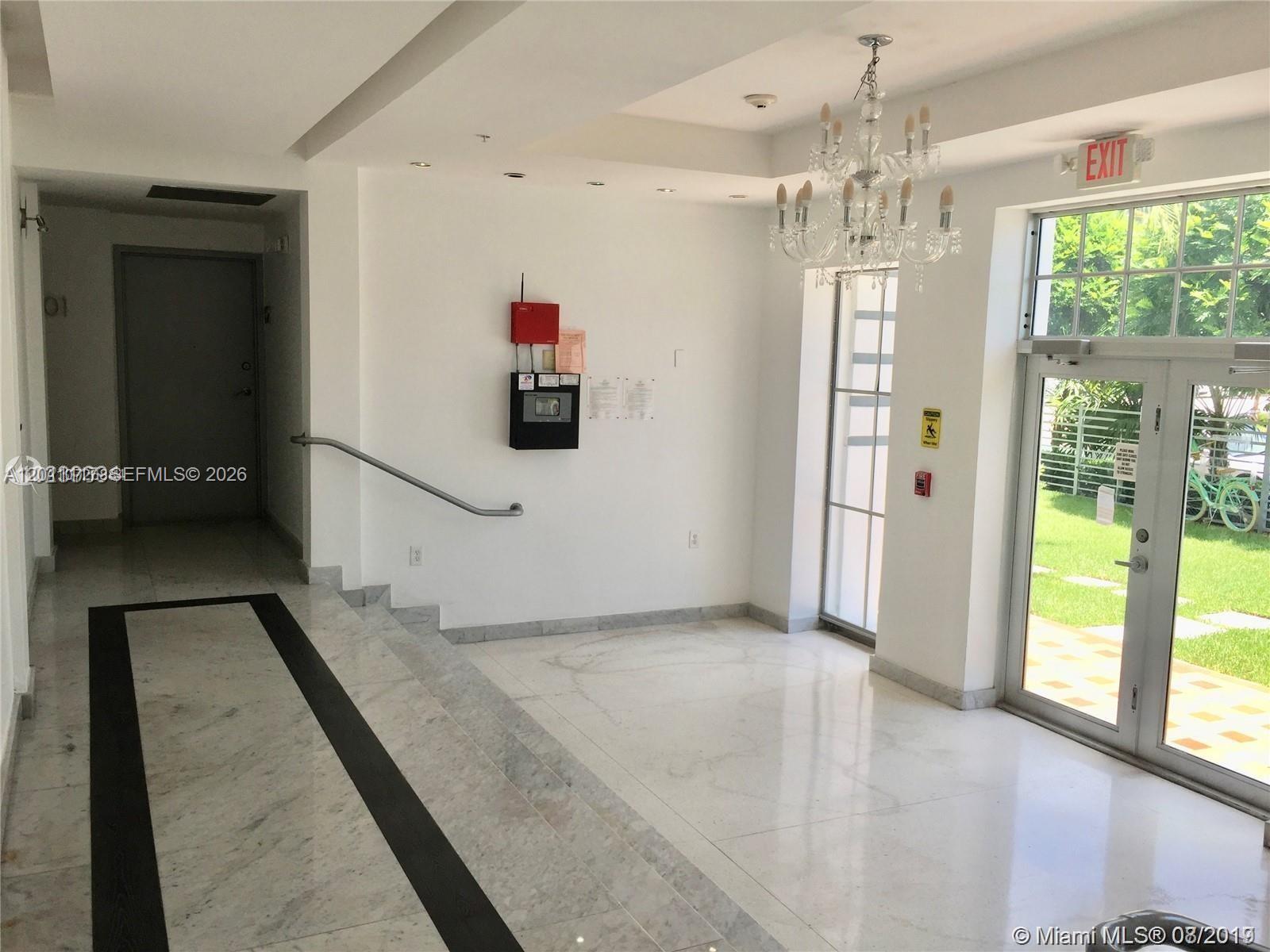 A bright lobby features marble floors, a chandelier, a staircase, and glass entry doors — 1600 Euclid Ave # 203, Miami Beach FL 33139, MIAMI BEACH, FL