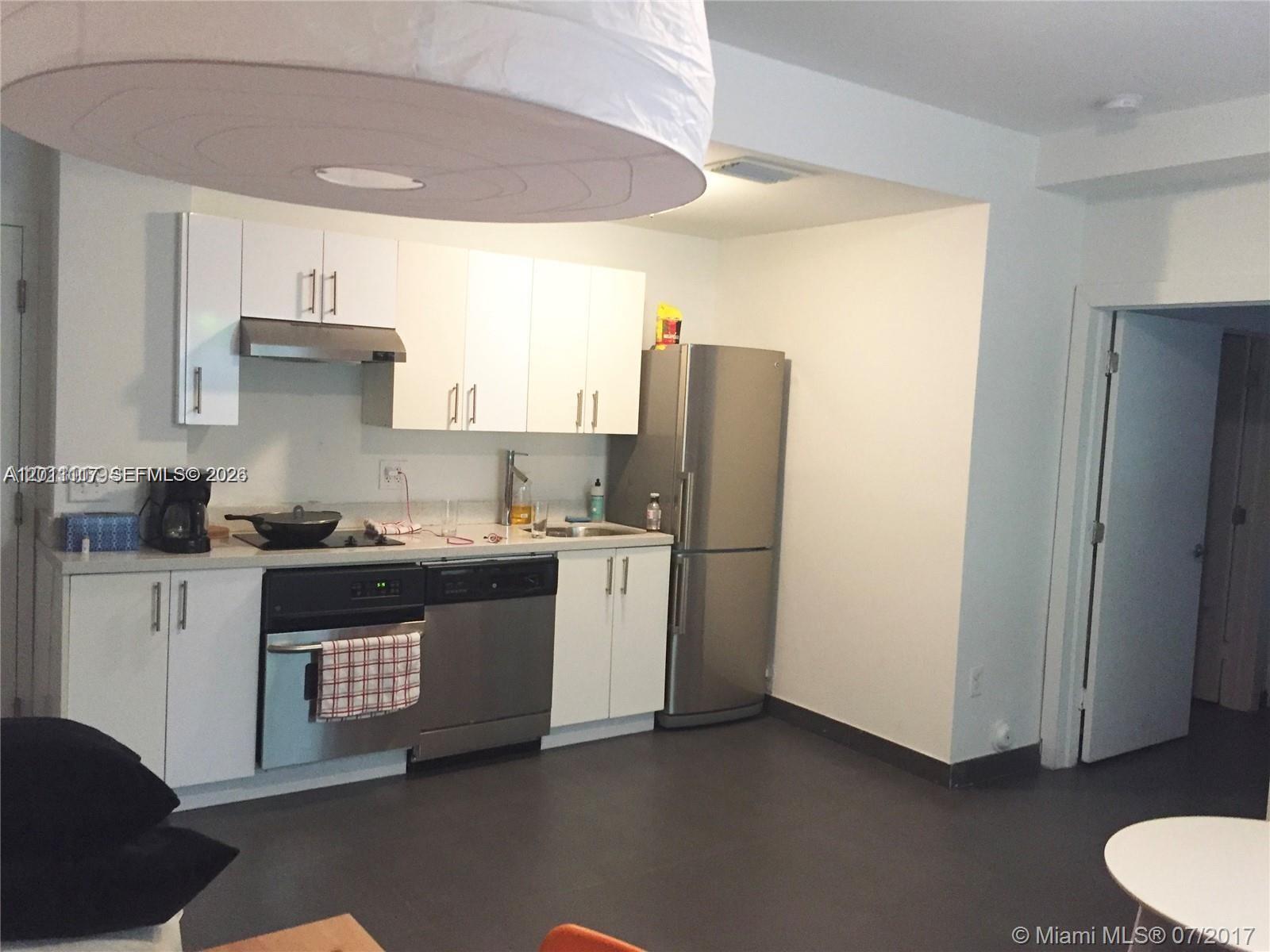 A kitchen features white cabinets, stainless steel appliances, and dark flooring — 1600 Euclid Ave # 203, Miami Beach FL 33139, MIAMI BEACH, FL