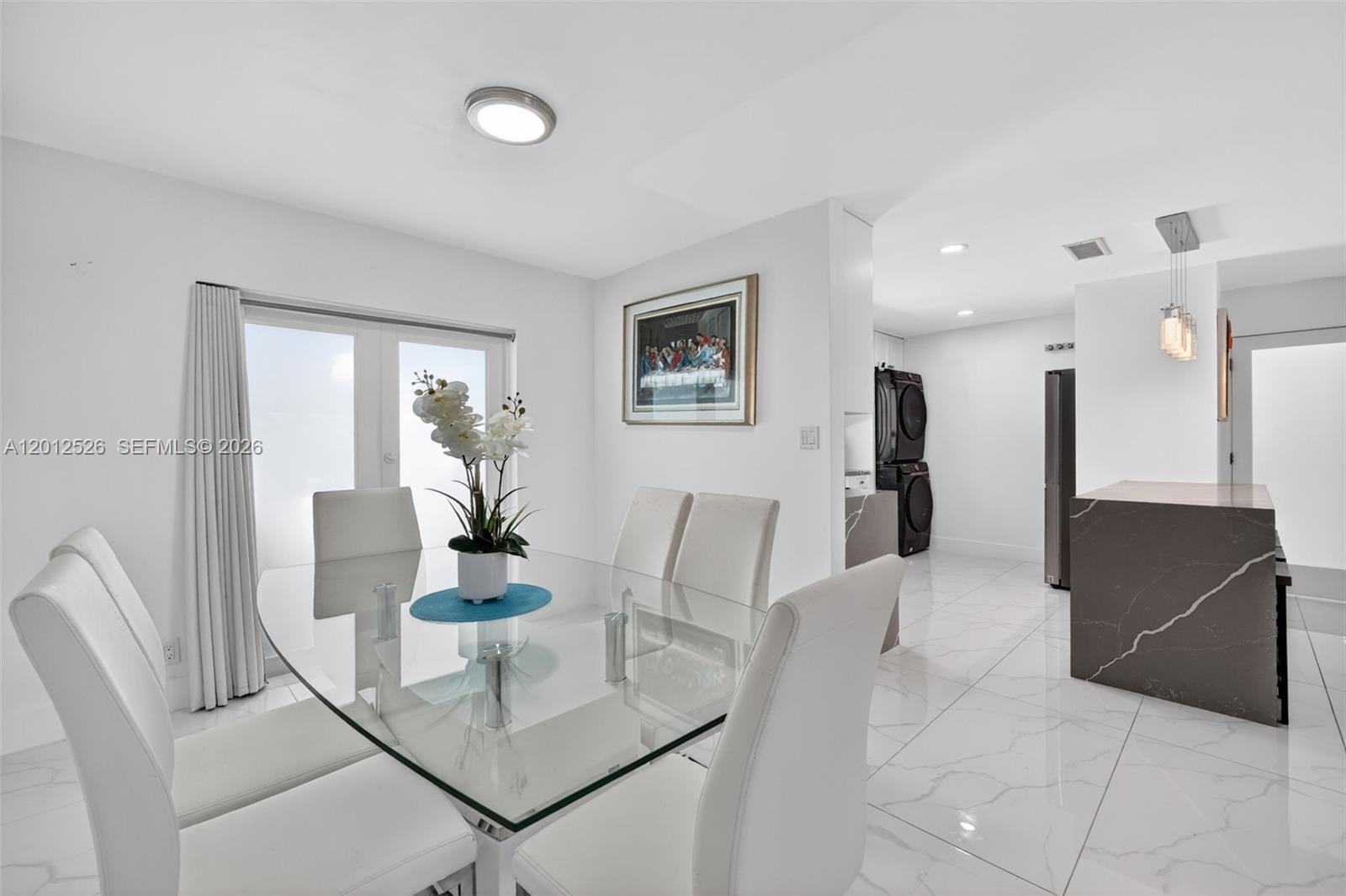 A dining area features a glass table, white chairs, and tile flooring, leading to a kitchen — 14234 SW 75th Ter, Miami FL 33183, MIAMI, FL