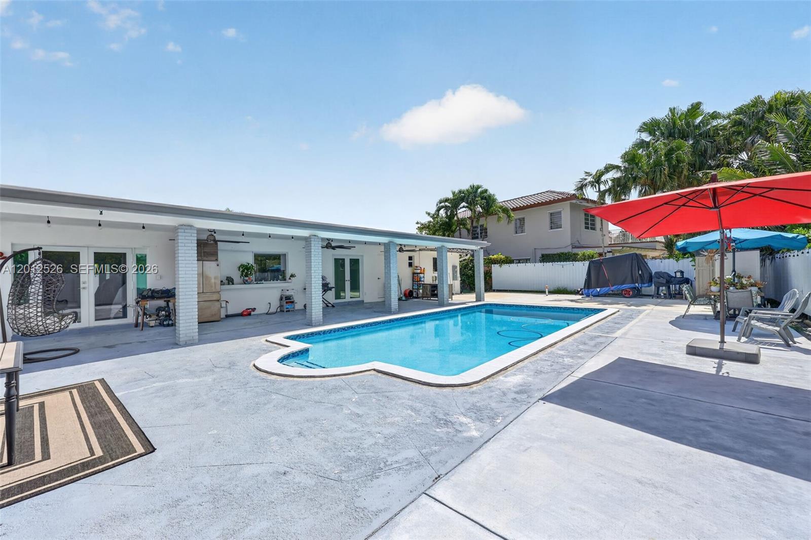 A backyard features a rectangular swimming pool, a covered patio, and a red umbrella — 14234 SW 75th Ter, Miami FL 33183, MIAMI, FL