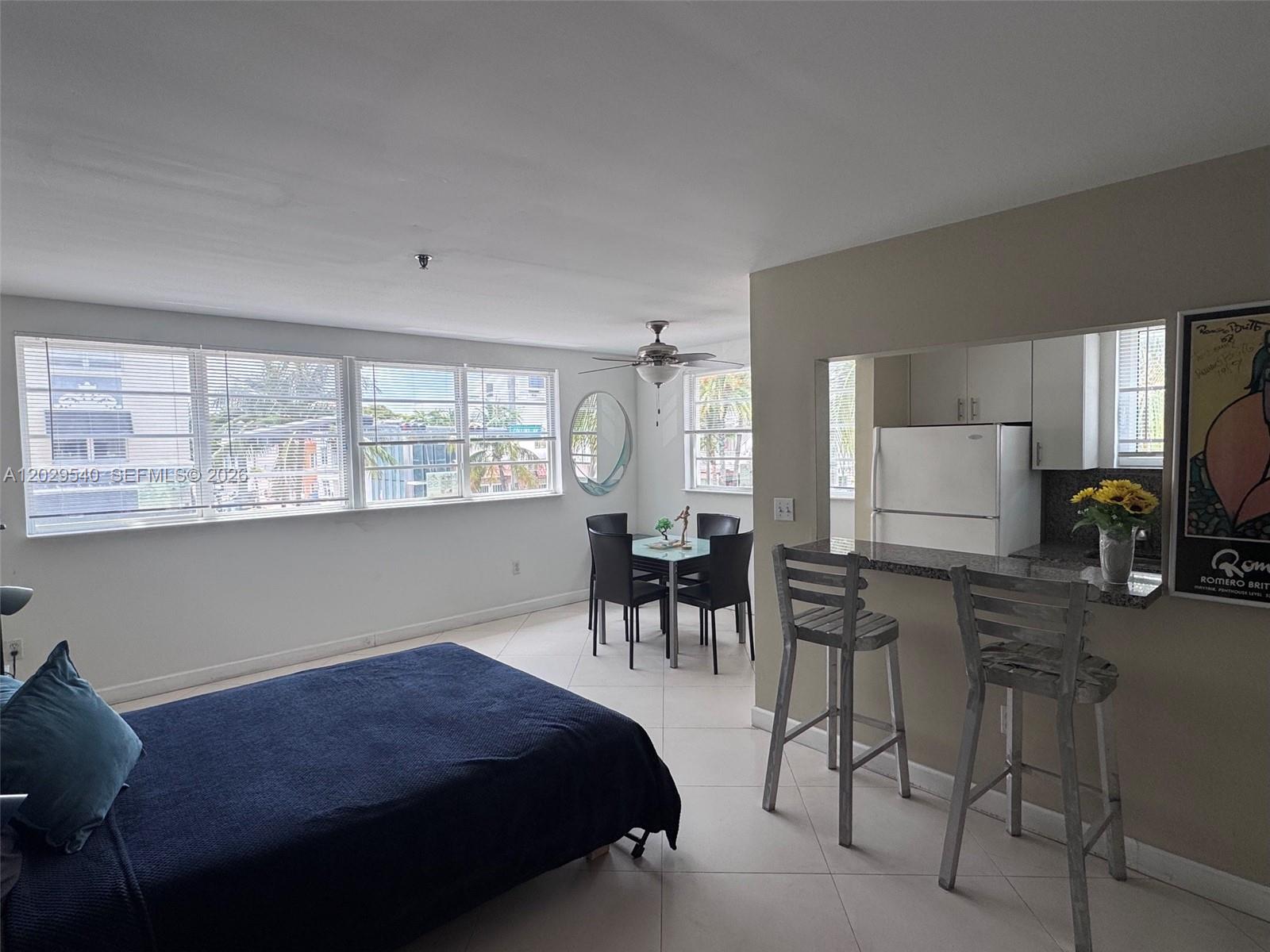 A studio apartment features a bed, a dining area, and a kitchen with a breakfast bar — 865 Collins Ave # 210, Miami Beach FL 33139, MIAMI BEACH, FL