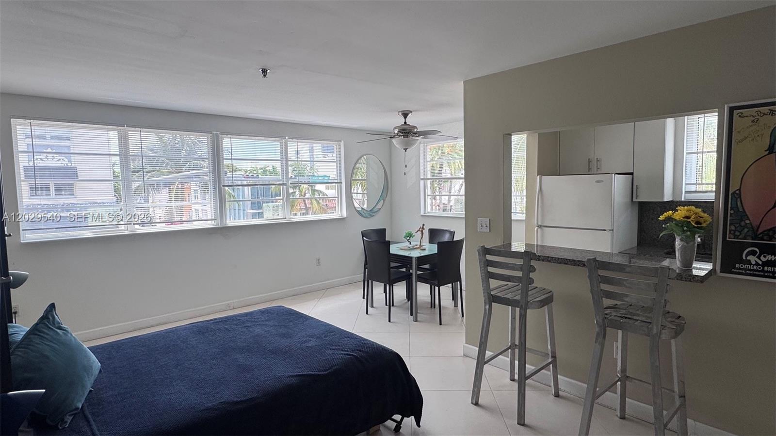 A studio apartment features a bed, a dining area, and a kitchen with a breakfast bar — 865 Collins Ave # 210, Miami Beach FL 33139, MIAMI BEACH, FL