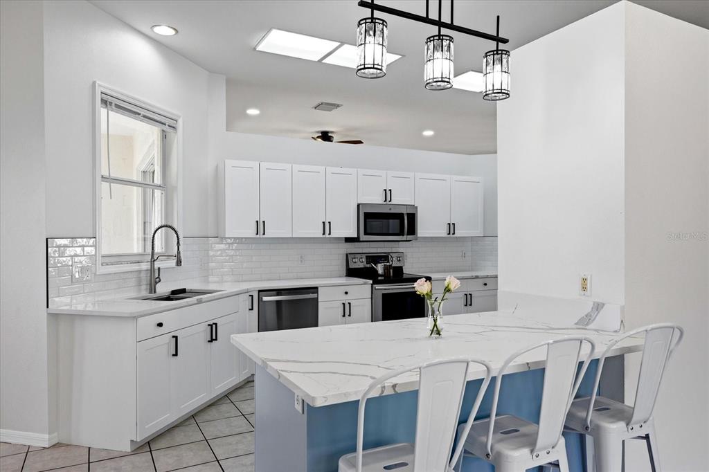 An open-concept kitchen with a blue island and a living room with a sectional sofa — 6223 ROCK CREEK CIRCLE, ELLENTON, FL