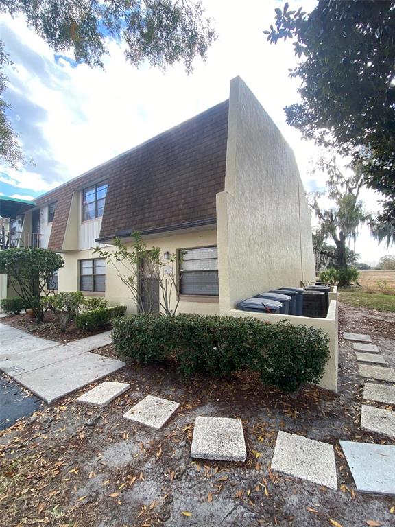 A two-story townhouse exterior with a brown shingled roof, beige stucco walls, and landscaping — 6120 TOPHER TRAIL UNIT 6120, MULBERRY, FL