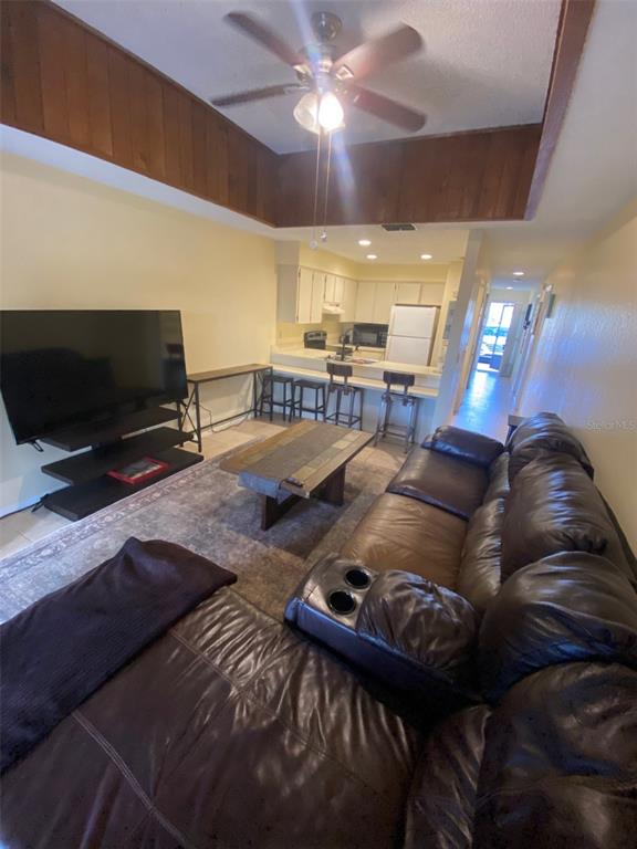 A living room with a brown leather sectional, coffee table, and an open kitchen beyond — 6120 TOPHER TRAIL UNIT 6120, MULBERRY, FL