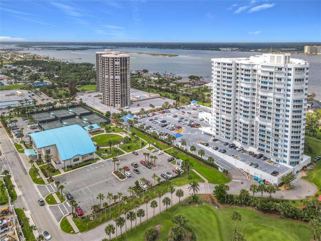 An aerial view shows two high-rise apartment buildings, a tennis court, and a parking lot — 2 OCEANS WEST BLVD UNIT 300, DAYTONA BEACH SHORES, FL