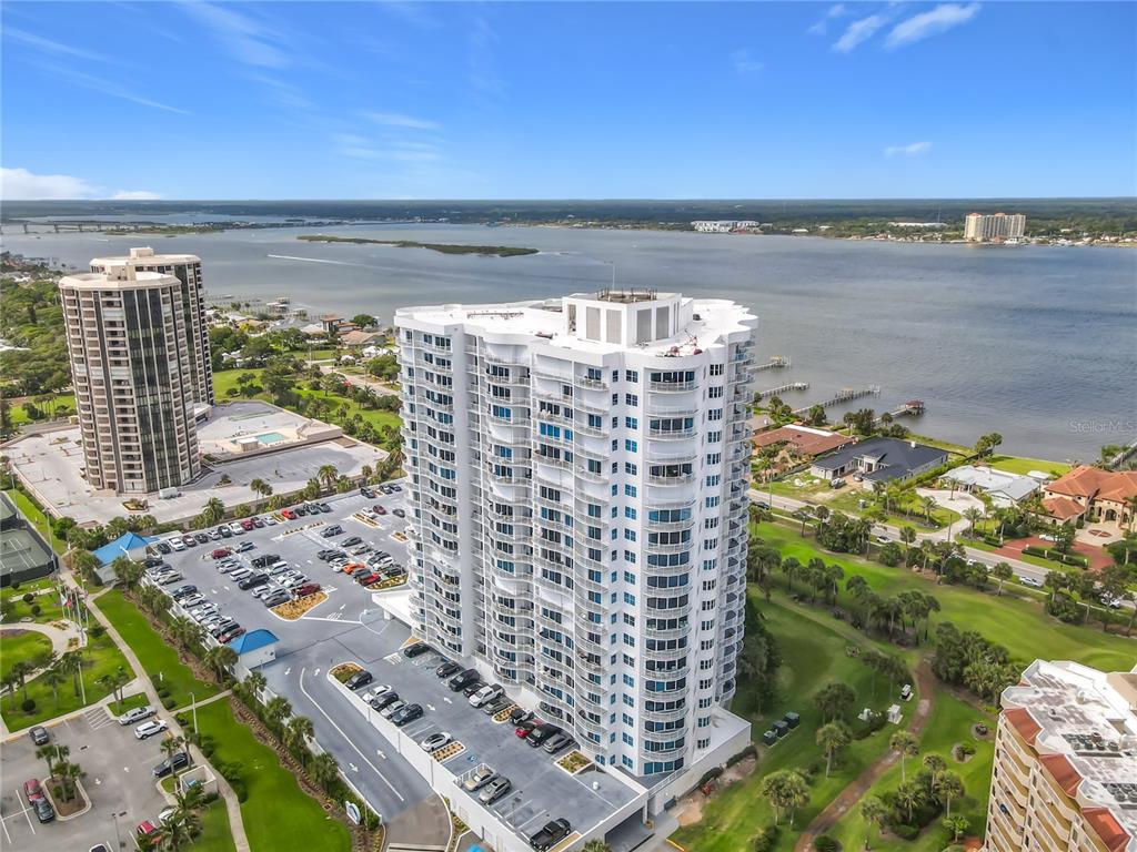 An aerial view shows two high-rise residential buildings situated near a large body of water — 2 OCEANS WEST BLVD UNIT 300, DAYTONA BEACH SHORES, FL
