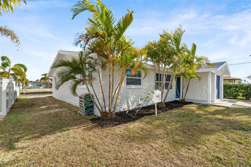 A white house with stone-textured siding and palm trees sits on a grassy lot — 13804 VICTOR AVENUE, HUDSON, FL