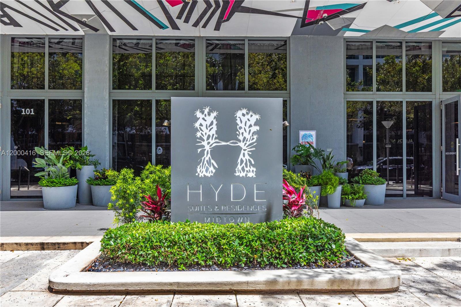 A gray sign for Hyde Suites & Residences stands in front of a glass-fronted building — 121 NE 34th St # 2602, Miami FL 33137, MIAMI, FL