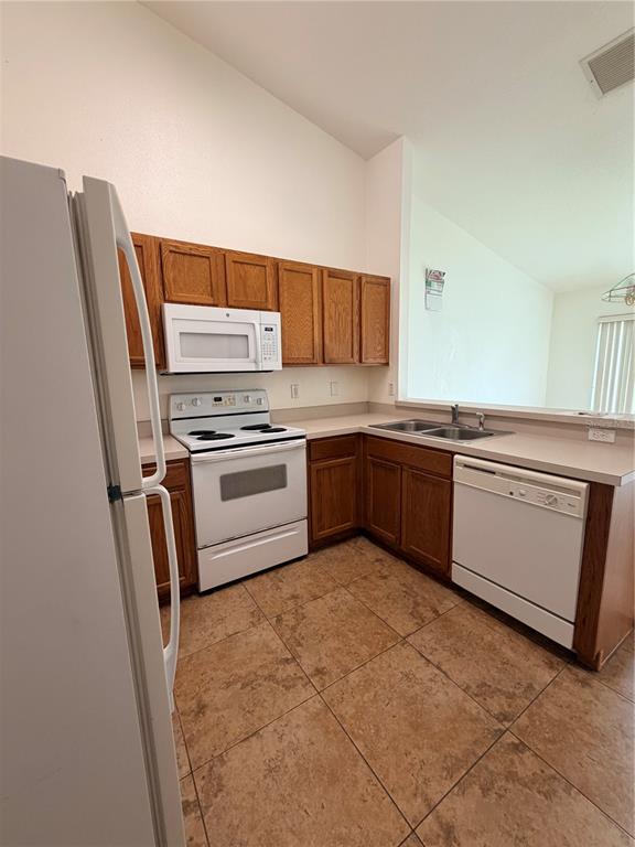 A kitchen with oak cabinets, white appliances, and tan tile flooring — 730 S GRAND HIGHWAY, CLERMONT, FL