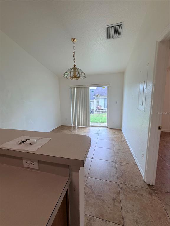 A dining area with tile flooring, a hanging light fixture, and a sliding glass door — 730 S GRAND HIGHWAY, CLERMONT, FL
