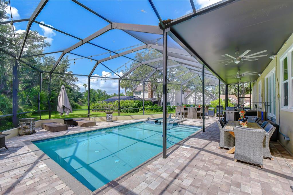 A screened-in patio features a rectangular swimming pool, brick pavers, and outdoor dining furniture — 1009 EMERALD CREEK DRIVE, VALRICO, FL