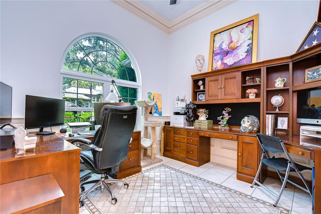 A home office features a large arched window, built-in wooden cabinetry, and tiled flooring — 1009 EMERALD CREEK DRIVE, VALRICO, FL