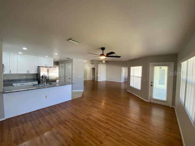 An open-concept kitchen and living area features white cabinetry, granite countertops, and wood-look flooring — 8427 SW 136TH STREET, OCALA, FL