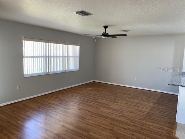 A living room features light gray walls, wood-look flooring, a ceiling fan, and vertical blinds — 8427 SW 136TH STREET, OCALA, FL