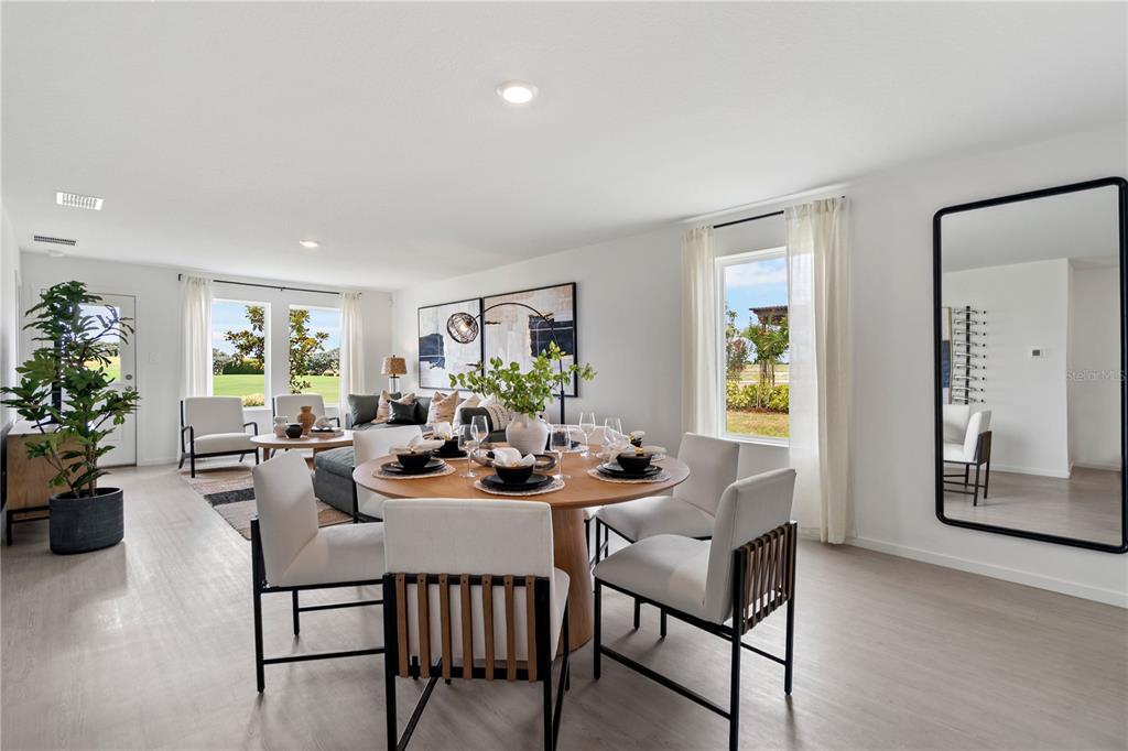 A bright, open-concept dining and living area features light wood flooring and large windows — 3448 ROVER ROAD, EAGLE LAKE, FL