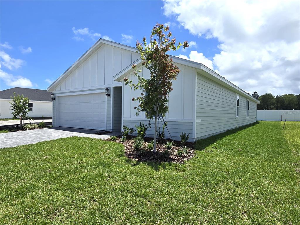 A single-story house with white board-and-batten siding, a two-car garage, and a landscaped front yard — 71 ARARAT DRIVE, PALM COAST, FL