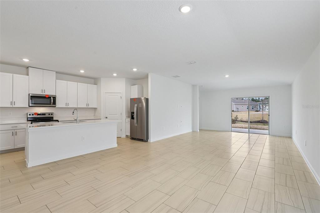 An open-concept kitchen and living area features white cabinetry, stainless steel appliances, and tile flooring — 71 ARARAT DRIVE, PALM COAST, FL
