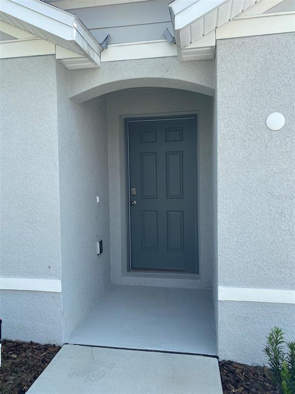 The exterior of a house features a gray front door set within a recessed entryway — 8864 SW 49TH CIRCLE, OCALA, FL