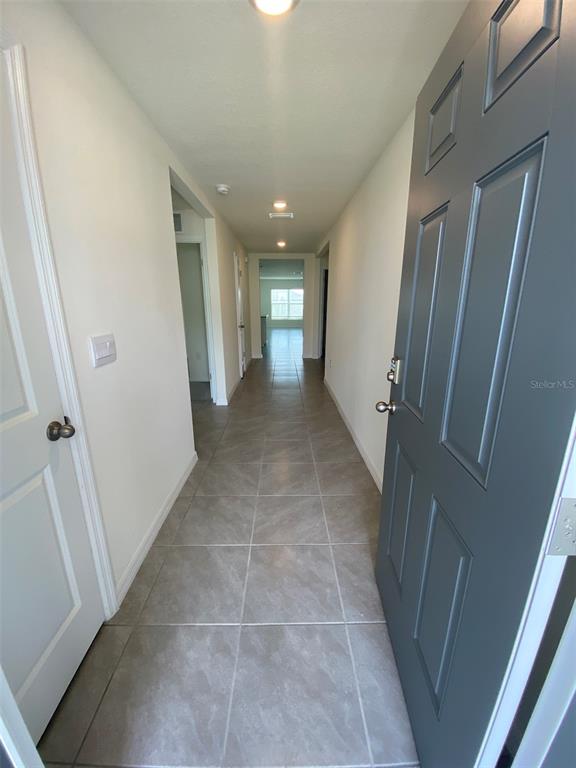 A hallway with light-colored tile flooring leads from an open dark gray door — 8864 SW 49TH CIRCLE, OCALA, FL
