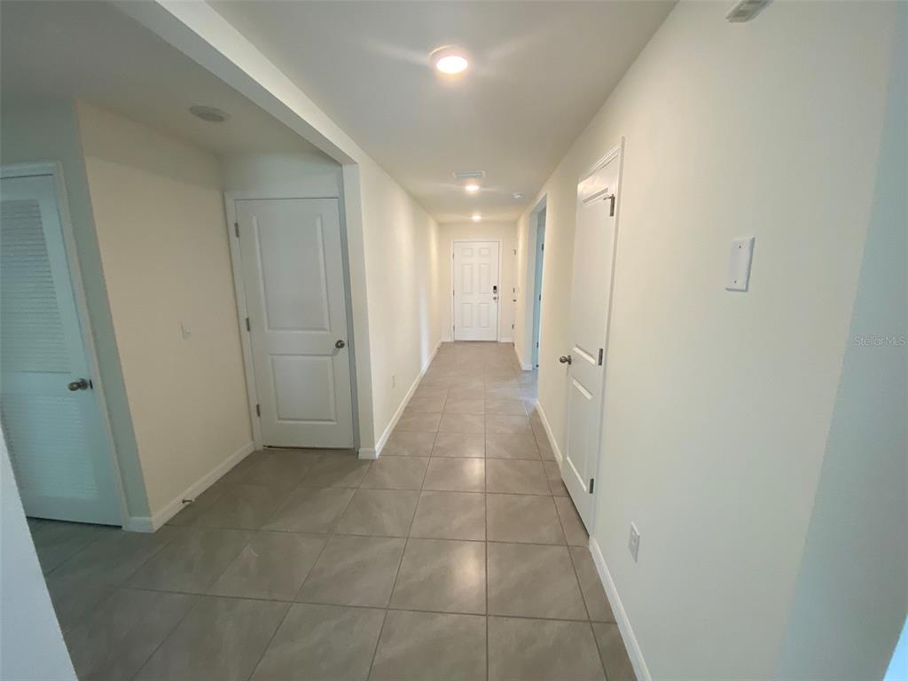 A hallway with light-colored walls, tiled flooring, and several white interior doors — 8864 SW 49TH CIRCLE, OCALA, FL
