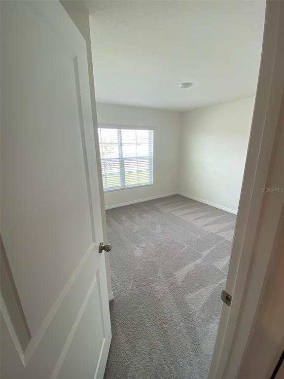 A view through an open doorway into an empty bedroom with gray carpet and blinds — 8864 SW 49TH CIRCLE, OCALA, FL