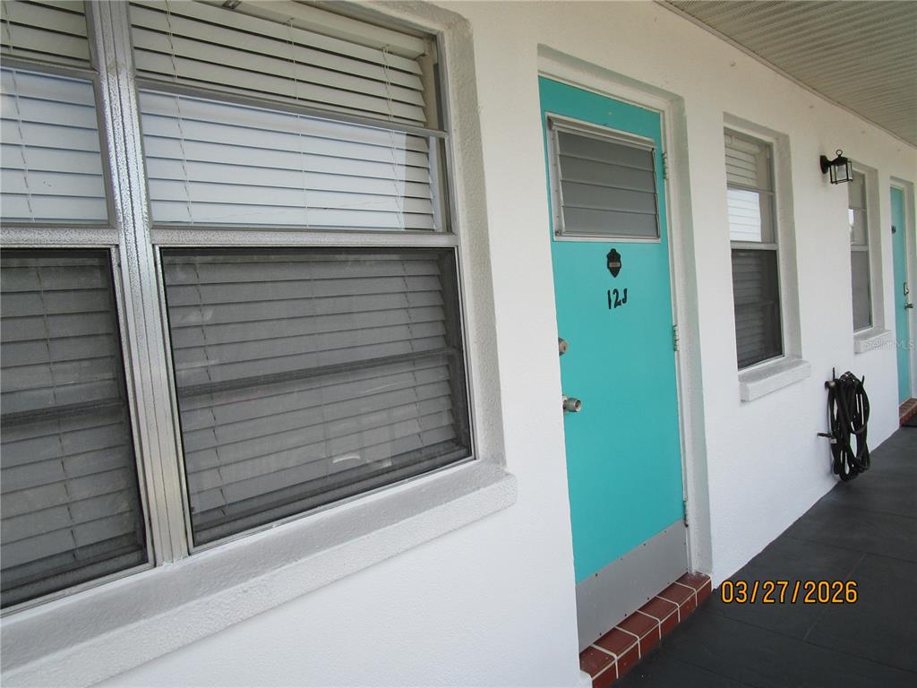 A turquoise front door with the number 12J is set in a white exterior wall — 6055 21ST STREET N UNIT 12, ST PETERSBURG, FL