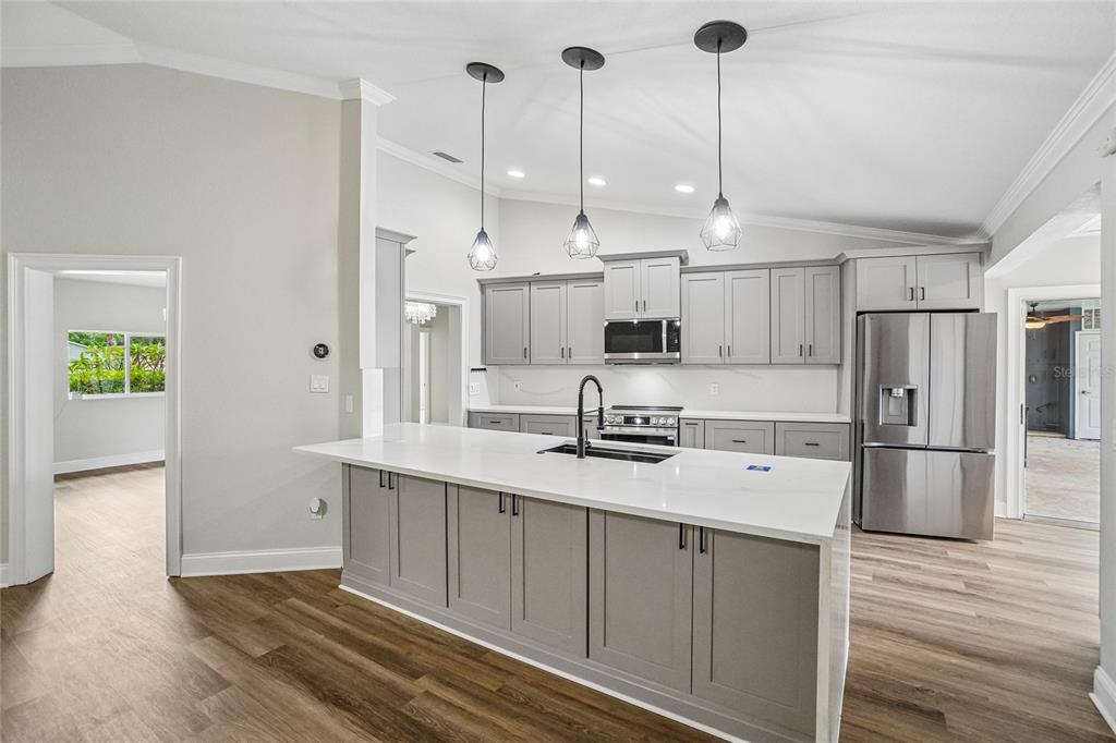A kitchen with gray cabinets, a white quartz island, and stainless steel appliances — 5609 EXECUTIVE DRIVE, NEW PORT RICHEY, FL