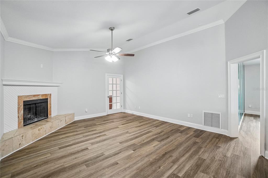 A living room with light gray walls, wood-look flooring, a fireplace, and a ceiling fan — 5609 EXECUTIVE DRIVE, NEW PORT RICHEY, FL