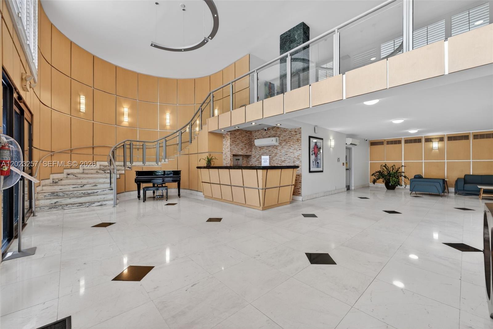 This lobby features a curved staircase, a reception desk, and light wood paneling — 6770 Indian Creek Dr # 5D, Miami Beach FL 33141, MIAMI BEACH, FL