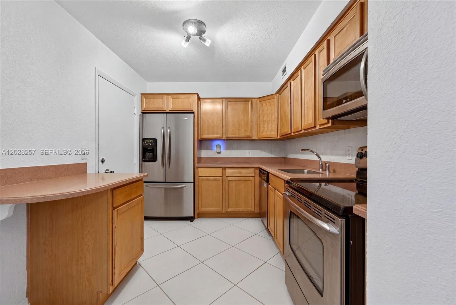 A kitchen features wood cabinets, stainless steel appliances, and a peninsula with a countertop — 6770 Indian Creek Dr # 5D, Miami Beach FL 33141, MIAMI BEACH, FL