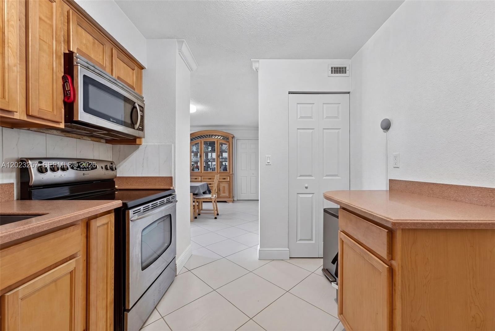 A kitchen features wooden cabinets, stainless steel appliances, and a tiled floor — 6770 Indian Creek Dr # 5D, Miami Beach FL 33141, MIAMI BEACH, FL