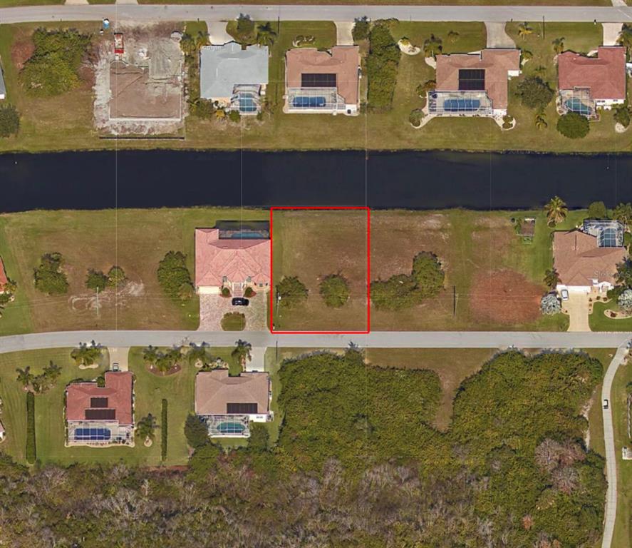 An aerial view shows a vacant rectangular lot situated between two houses along a canal — 117 MEDALIST ROAD, ROTONDA WEST, FL