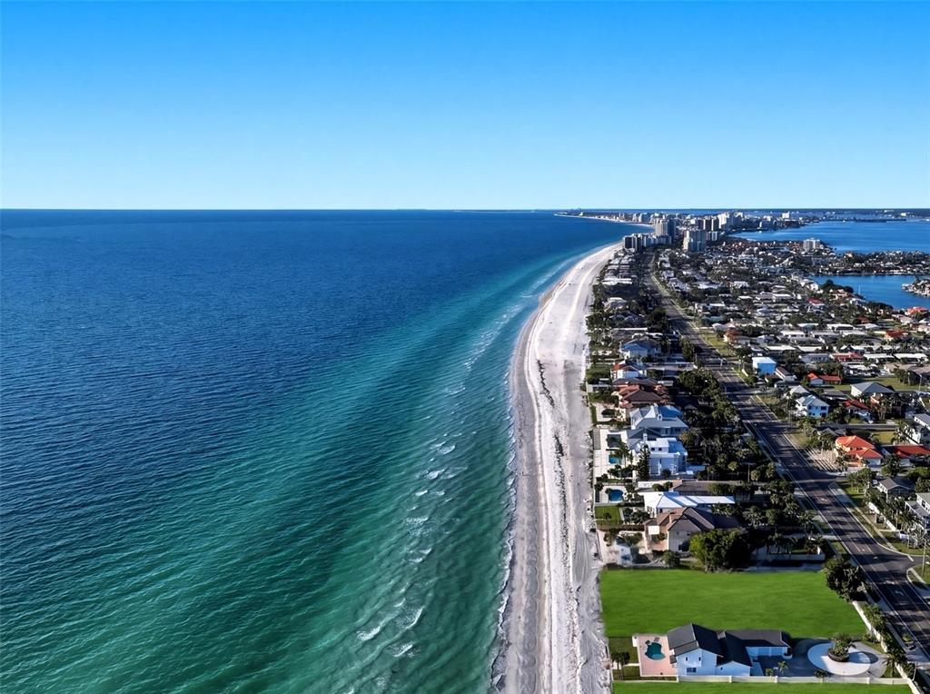 An aerial view shows three residential properties, including one vacant lot, along a paved road — 1420 and 1440 GULF BOULEVARD, BELLEAIR SHORE, FL