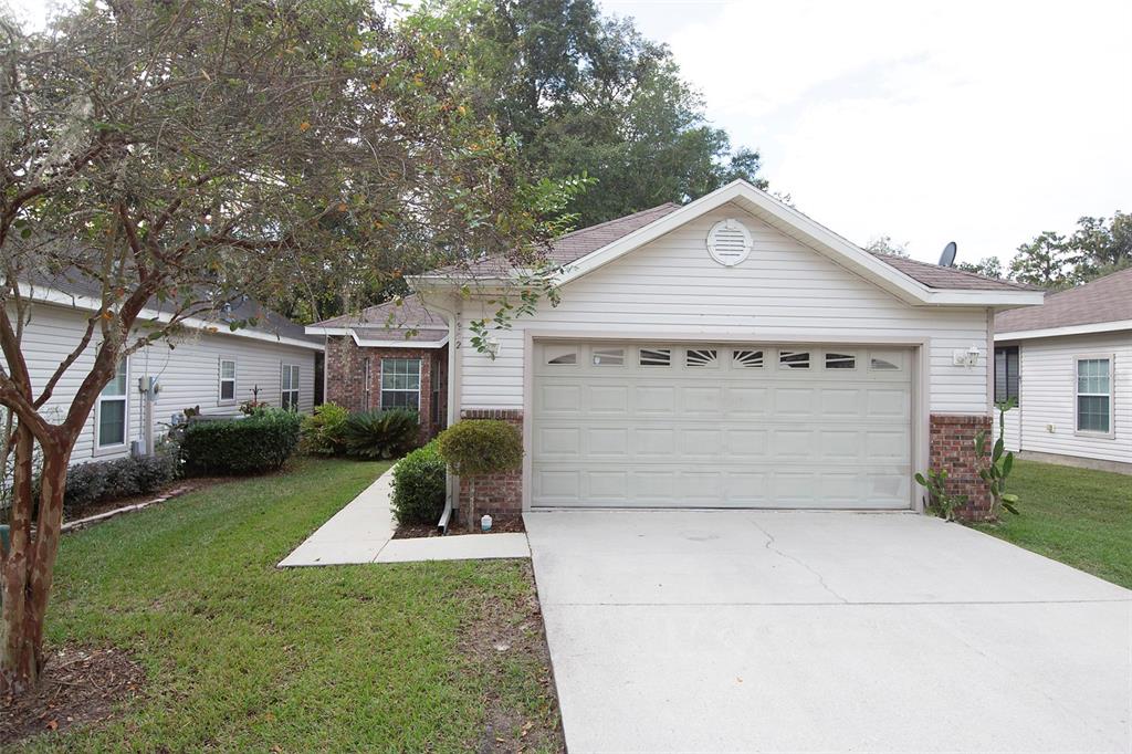 A single-story house with a white garage door, brick accents, and a concrete driveway — 7952 NW 51ST WAY, GAINESVILLE, FL