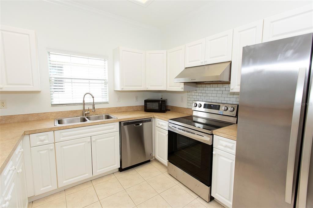 A kitchen with white cabinets, stainless steel appliances, and tan countertops — 7952 NW 51ST WAY, GAINESVILLE, FL