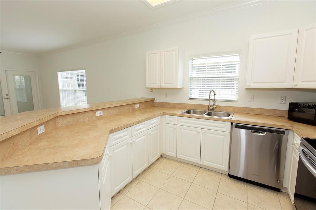 A kitchen with white cabinets, beige laminate countertops, stainless steel appliances, and tile flooring — 7952 NW 51ST WAY, GAINESVILLE, FL