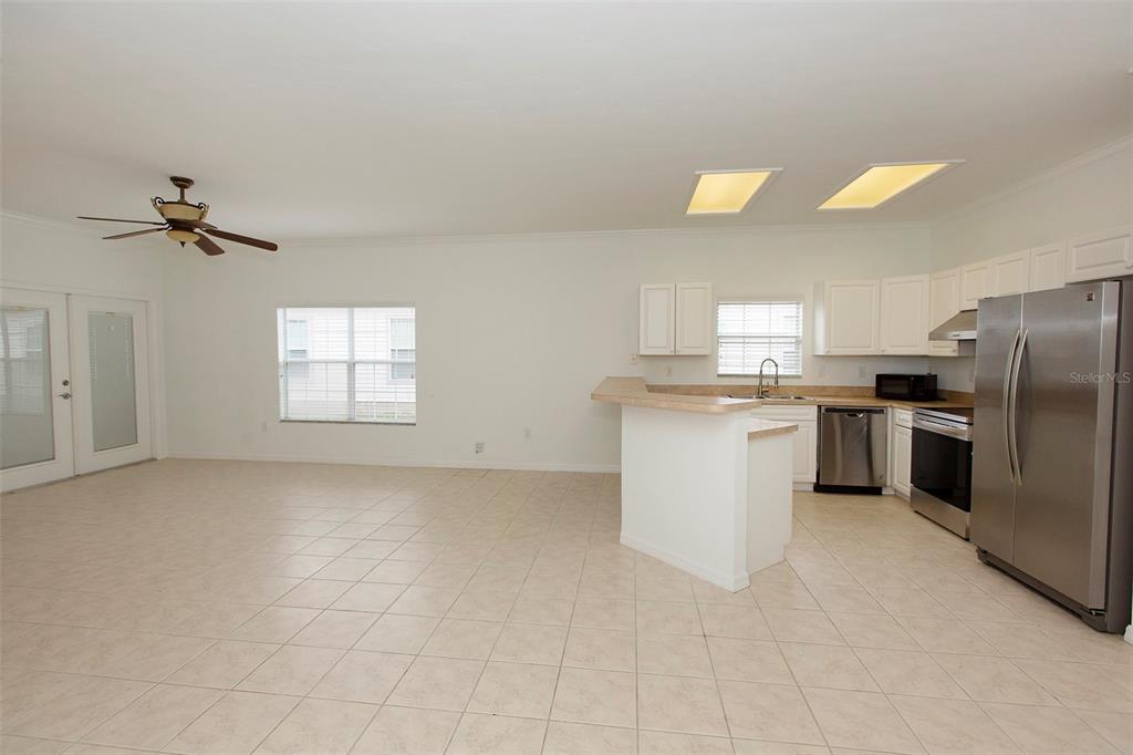 An open-concept kitchen and living area features white cabinets, stainless steel appliances, and tile flooring — 7952 NW 51ST WAY, GAINESVILLE, FL