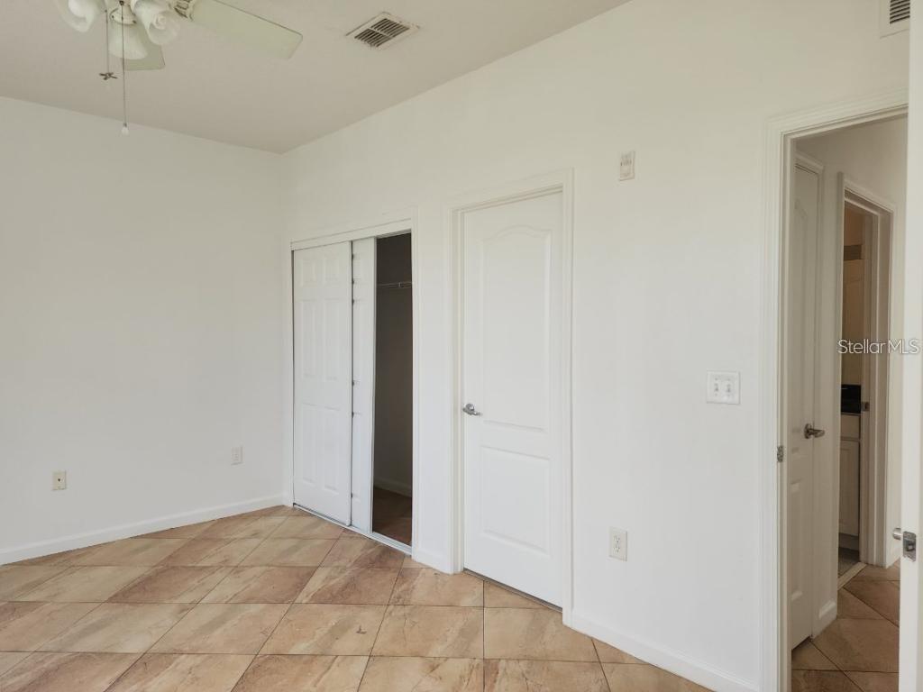 A room with white walls, tile flooring, a ceiling fan, a closet, and two doors — 5255 CANE ISLAND LOOP UNIT 304, KISSIMMEE, FL